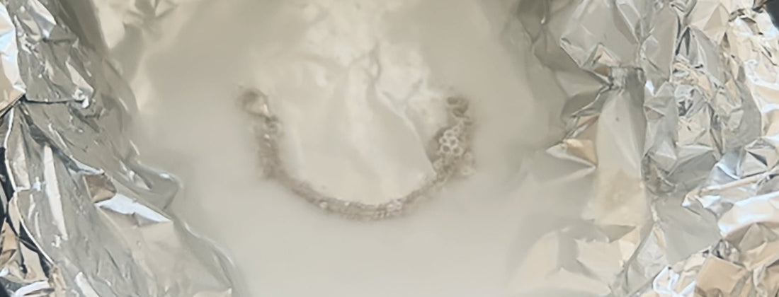 A silver piece lying in a bowl with aluminium foil and a baking soda solution — the method for removing tarnish