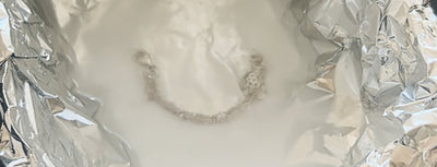 A silver piece lying in a bowl with aluminium foil and a baking soda solution — the method for removing tarnish