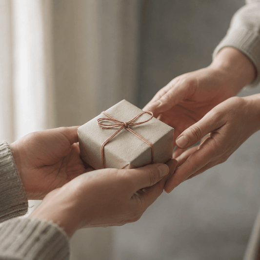 Two hands passing a small wrapped gift box