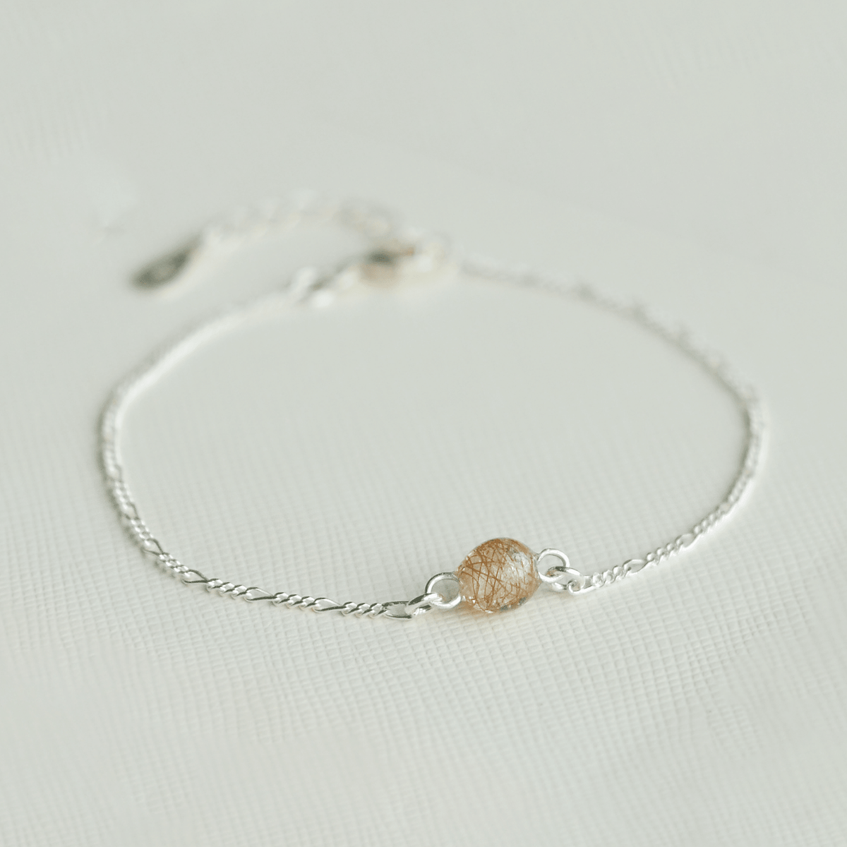 Lærke armbånd i 925 sterling sølv med en håndlavet resinperle i perlehvid med rødt hår fra rød hest – med fokus på perlen. I firkant format.