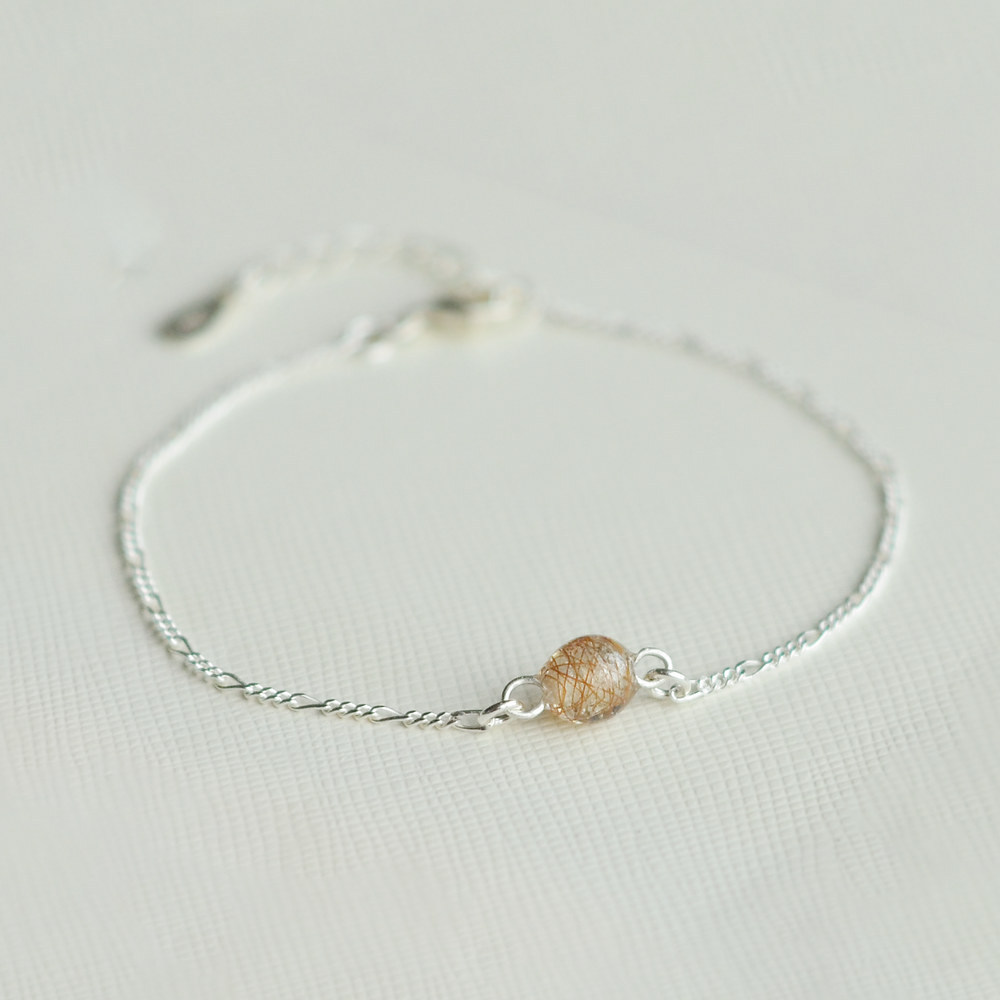 Lærke armbånd i 925 sterling sølv med en håndlavet resinperle i perlehvid med rødt hår fra rød hest – med fokus på perlen. I firkant format.